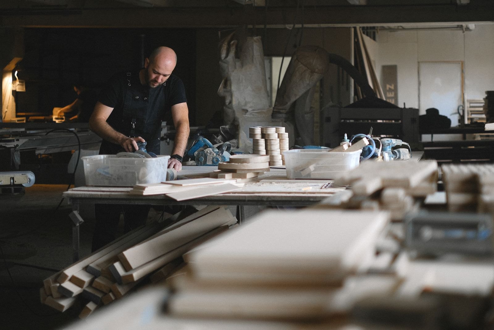 Woodworker in black shirt assembling wooden components at workbench in carpentry shop