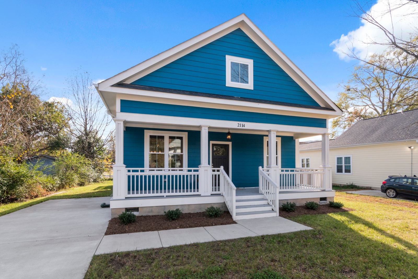 Teal and white cottage-style home with wraparound porch at 214H